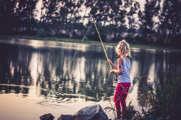 child fishing on the lake at sunset time