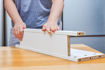 Furniture assemble at home, woman putting together parts of chipboard.