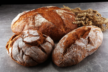 Different kinds of bread and bread rolls on board from above. Kitchen or bakery