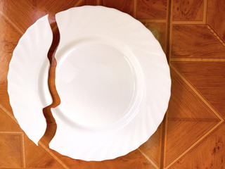 Broken white plate on the table, on the floor.