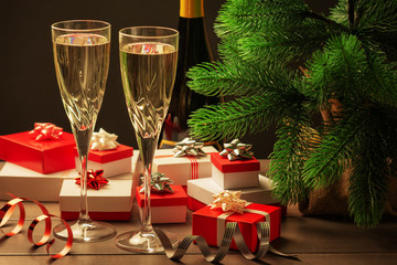 Christmas composition. Two champagne glasses, lots of red and white gift boxes, a Christmas tree and decorative ribbons.