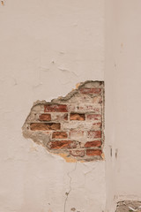 Brick wall with collapsed white plaster 