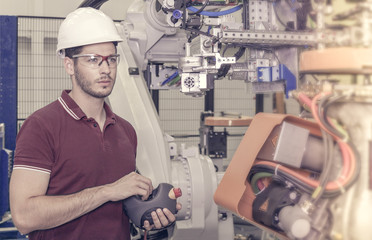engineer checks the connectivity of some robots in a car production plant. the assembly line has to...
