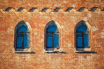 old weathered brick wall with windows in gothic style