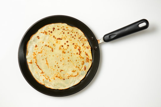 Crepe closeup, thin pancake on a frying pan, white background