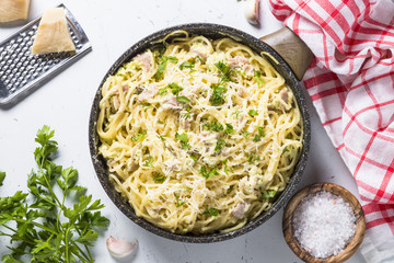 Pasta carbonara with bacon and cream sauce on white.