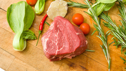 Raw marbled beef with vegetables on a cutting board