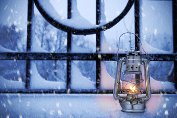 Vintage lantern in the snow against the background of the fence. Winter evening.