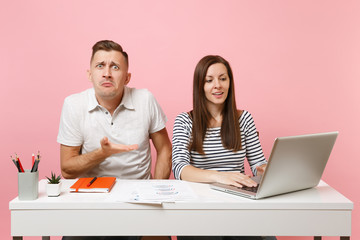 Two young tired business woman man colleagues sit work at white desk with contemporary laptop...