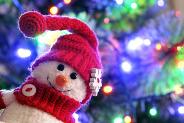 Face of a snowman on the background of the Christmas tree.