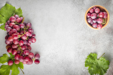 Red grapes with leaves of grapes on a stone table. Top view. Free space for text.