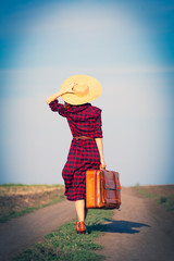 Beautiful girl in plaid dress with bag on countryside