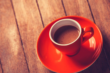 Little orange cup of the coffee on a wooden table