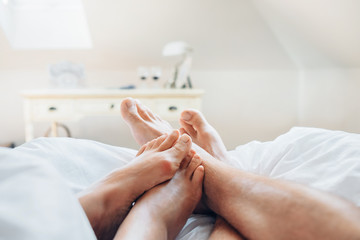 Couple in love meet morning in bed. Close up image man and woman feets
