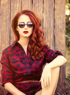 Beautiful girl in plaid dress with sunglasses on wooden background at countryside
