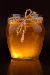 Fresh floral honey in a glass jar on a black isolate.