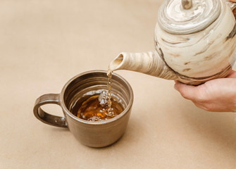 Tea pouring into tea cup from kettle