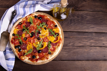 Italian pizza, towel and bottle of oil on a wooden table.