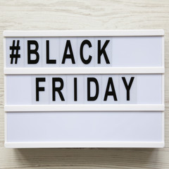'Black friday' word on lightbox over white wooden background, overhead view. Flat lay, from above, top view.