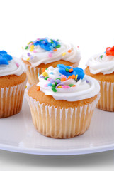 Frosted Vanilla Cupcakes With Sprinkles On A Plate