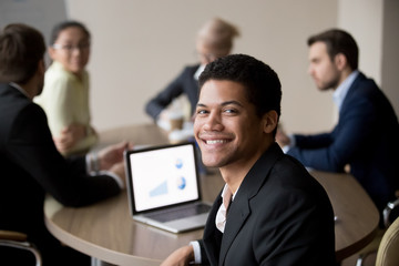 Portrait of smiling African American male employee posing for picture during office business...