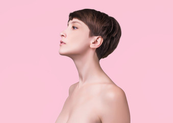 Beautiful woman. Female face close up. Portrait of young caucasian woman at studio isolated on pink. Fresh skin and beauty concept. Short haircut, long neck, perfect skin