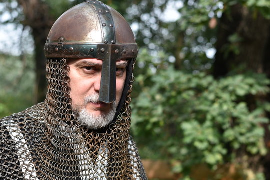 Three-quarters portrait of mature man dressed as a medieval warrior, wearing a nasal helm with aventail.