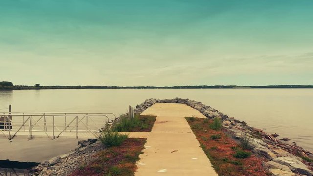 Aerial Fly Over Pier Into Lake. an aerial view moving down a pier sidewalk over into the lake. Slow motion