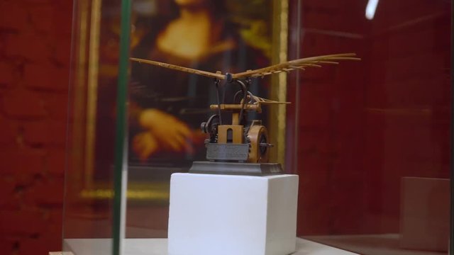 Flying machine showpiece antique model designed by Leonardo Da Vinci in a glass cube on the Mona Lisa reproduction background