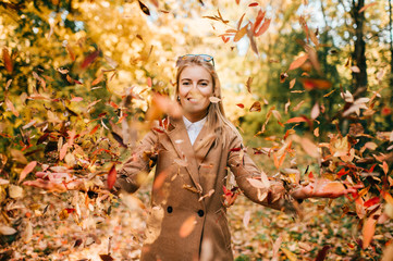 Young business fashionable dressed woman playing in park. Autumn fun. Beautiful blonde happy...