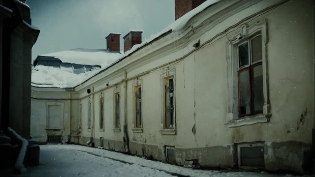 Snow and old, rustic building in winter time. Cold weather, snowfall and dark atmosphere with grunge walls.