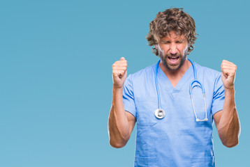 Naklejka premium Handsome hispanic surgeon doctor man over isolated background excited for success with arms raised celebrating victory smiling. Winner concept.