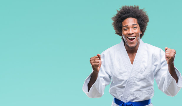 Afro american man wearing karate kimono over isolated background celebrating surprised and amazed for success with arms raised and open eyes. Winner concept.