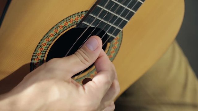 Close up shot of guitarist's hand. He plays on acoustic guitar.