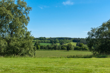 Cumnock, Ayrshire, Scotland, UK - June 18, 2012: Bucolic rural landscape with green pastures and darker forests under ble sky.