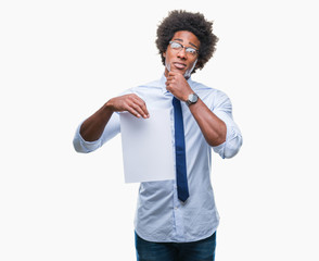 Afro american man holding blank paper contract over isolated background serious face thinking about...