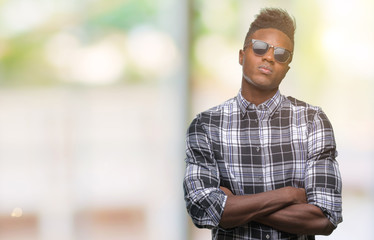 Young african american man wearing sunglasses over isolated background skeptic and nervous,...