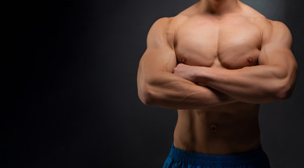 Fototapeta premium Sports wallpaper on dark background. Power athletic guy bodybuilder. Sport nutrition banner.