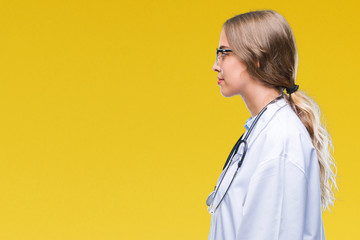 Beautiful young blonde doctor woman wearing medical uniform over isolated background looking to...