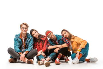 fashionable hipster friends sitting on floor and laying heads on each other shoulders isolated on white