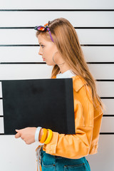 side view of arrested hipster girl posing with empty prison board in front of police line up