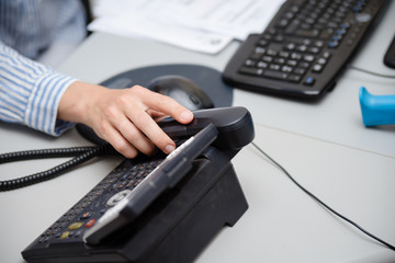 Close up of dialing a telephone device at office desk background, digital communication technology...
