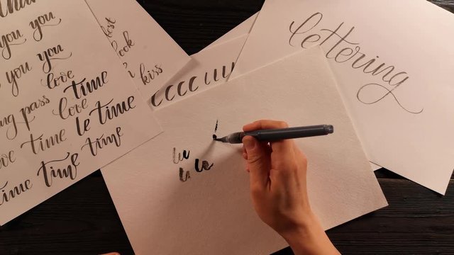hand with pen brush is trying to do the lettering exercise and fails