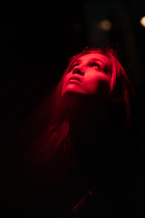 Portrait of girl with reflection of herself looking up on red lights