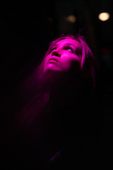 Portrait of girl with reflection of herself looking up on pink lights