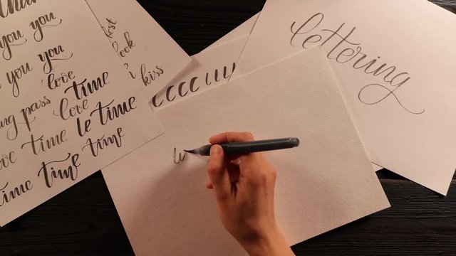 hand with pen brush is trying to do the lettering exercise and fails