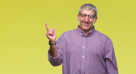 Naklejka premium Handsome senior man wearing glasses over isolated background with a big smile on face, pointing with hand and finger to the side looking at the camera.