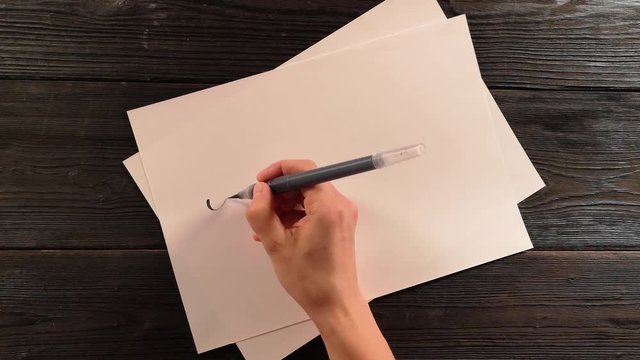 hand with penbrush writes the word lettering