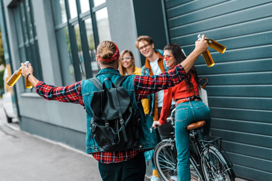 excited male hipster brought beer to happy friends on street with bicycle