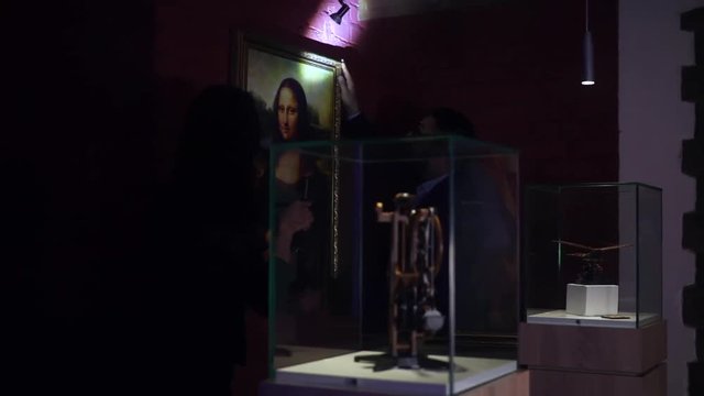Young man and a woman with flashlights are trying to make robbery museum and stealing Mona Lisa from gallery collection